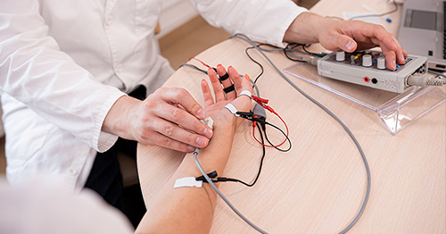 A clinician doing electromyography (EMG) nerve testing on a person's forearm.