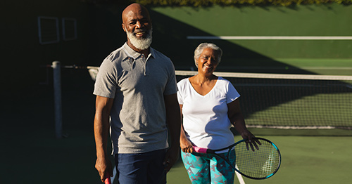 An older couple posing on the tennis court.