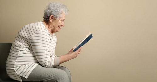 An older woman with kyphosis sitting hunched over.