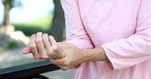 A woman grasping her hand in pain.