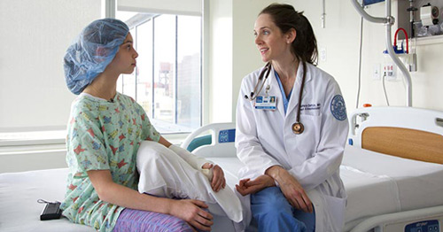 A child patient sitting with anesthesiologist Dr. Kate DelPizzo.