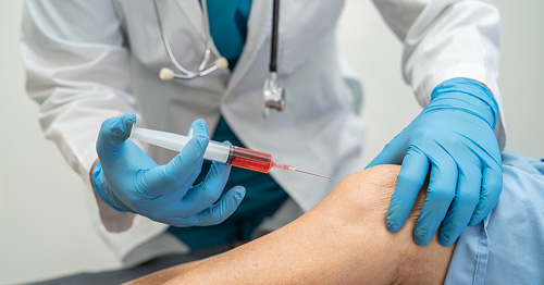 A doctor injecting platelet-rich plasma into a patient's knee.