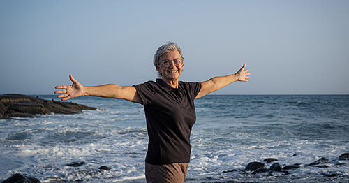 Smiling senior woman holding her arms outstretched.