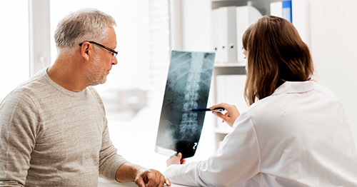 A doctor and a patient reviewing a spinal X-ray.