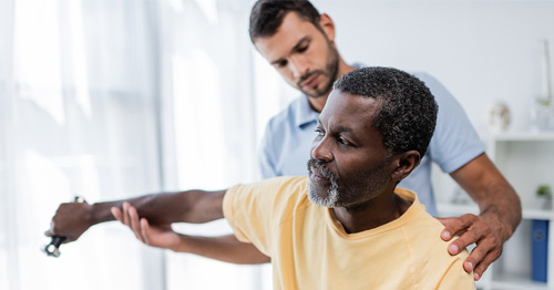 A middle-aged man getting physical therapy for the upper arm muscles.