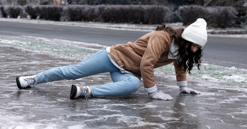 A woman slipping on ice and bracing her fall with her hands.