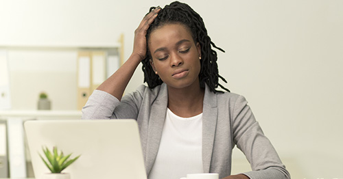 A woman with closed eyes holding her head.