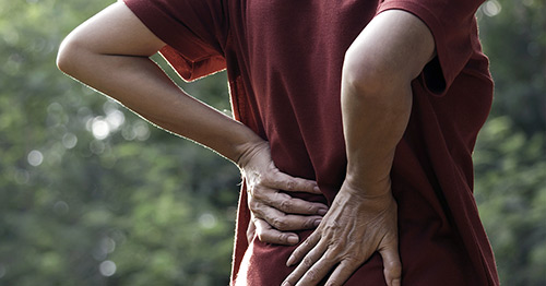 A woman holding her lower back in pain.