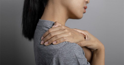 Woman in pain grasping her chest and shoulder area.